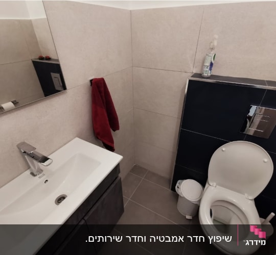 חדר שירותים משופץ ומעוצב עם אסלה תלויה, ארון כיור וחיפוי קירות